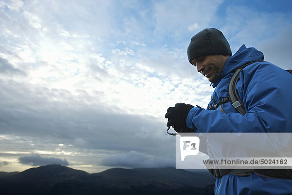 Hiker using digital camera on hillside