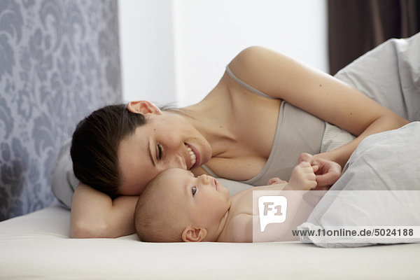 Frau und Baby im Bett liegend