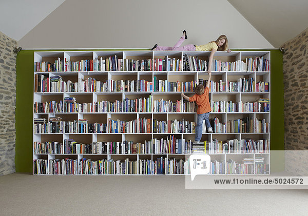 Kinder klettern im Bücherregal