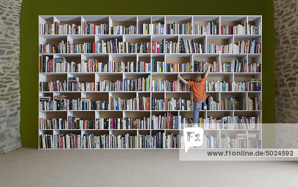 Junge klettert auf Bücherregale