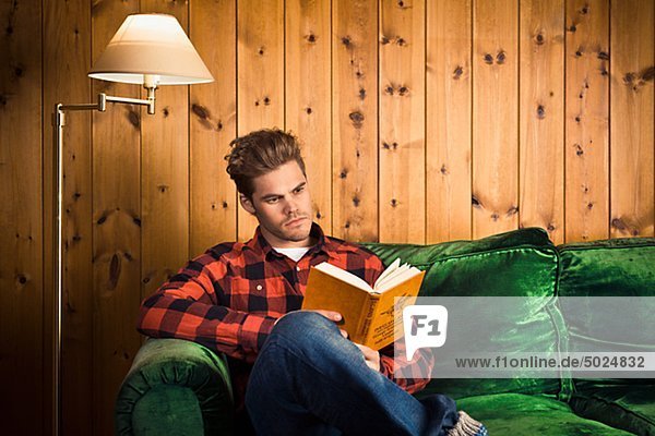 Young man reading book on couch
