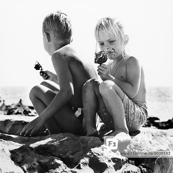 Jungen und Mädchen am Strand Eis essen