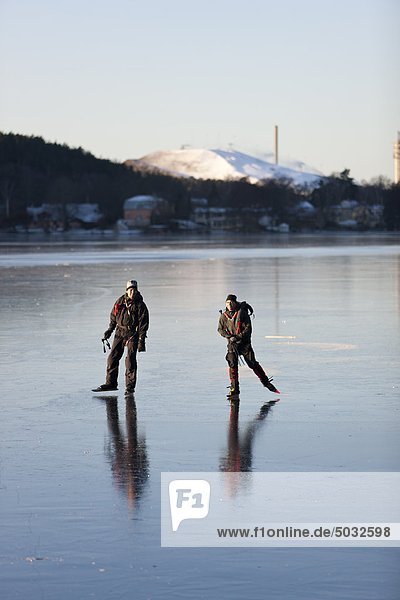 Two people ice skating on frozen lake