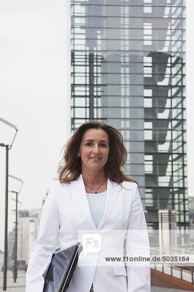 Geschäftsfrau mit Laptop am Rhein und Kranhaus im Hintergrund  lächelnd  Portrait