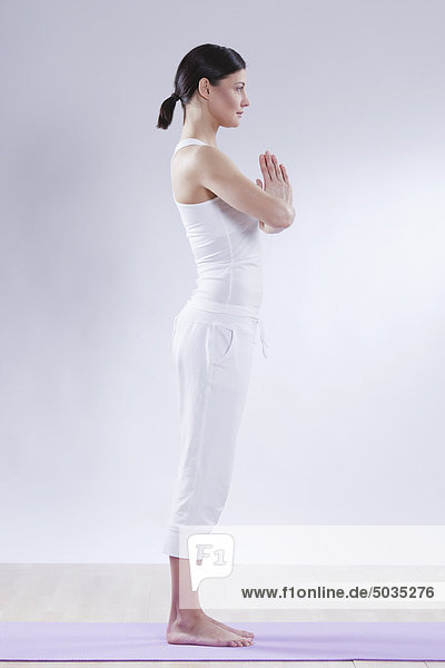 Mid adult woman doing yoga against white background