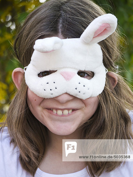 Close up of girl wearing easter bunny mask  smiling  portrait