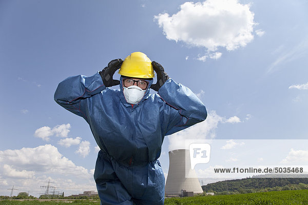 Man with protective workwear covering his ears in field at AKW Isar
