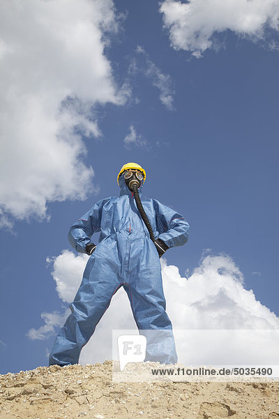 Man in protective workwear standing on top of sand dune