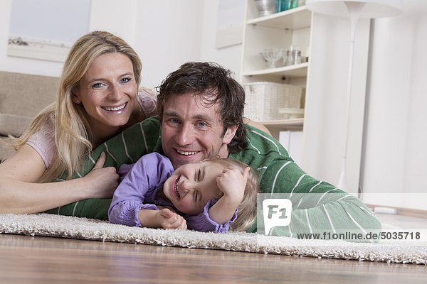 Deutschland  Bayern  München  Familie auf Teppich liegend  lächelnd