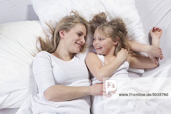 Germany  Bavaria  Munich  Mother and daughter lying on bed