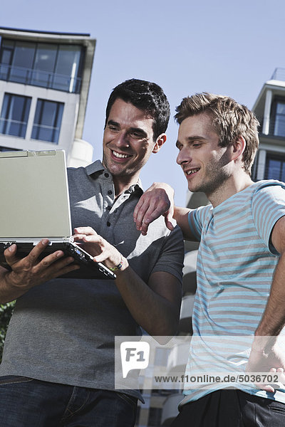 Männer diskutieren und benutzen Laptop