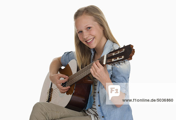 Girl playing guitar against white background  smiling  portrait