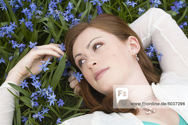 Rothaarige junge Frau liegen in einem Feld blau blumen, Whitby, Ontario, Kanada