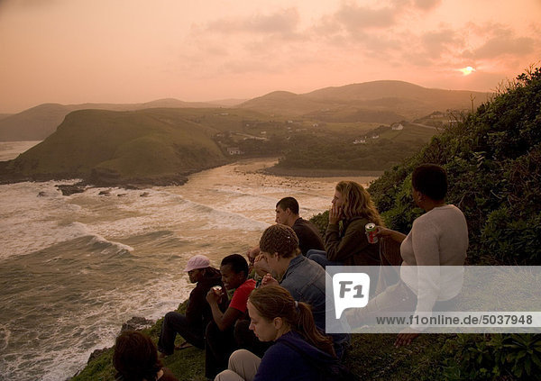 A group of tourists sit hillside overlooking Coffee Bay enjoying the sunset  Transkei  South Africa