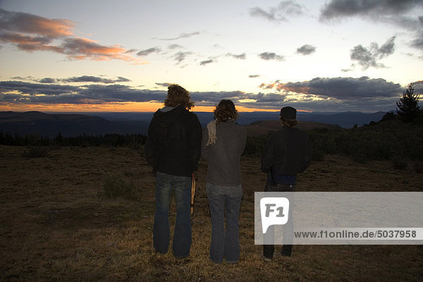 Three people viewing sunset in field by Hogsback Mountain  Amatola Mountains of South Africa