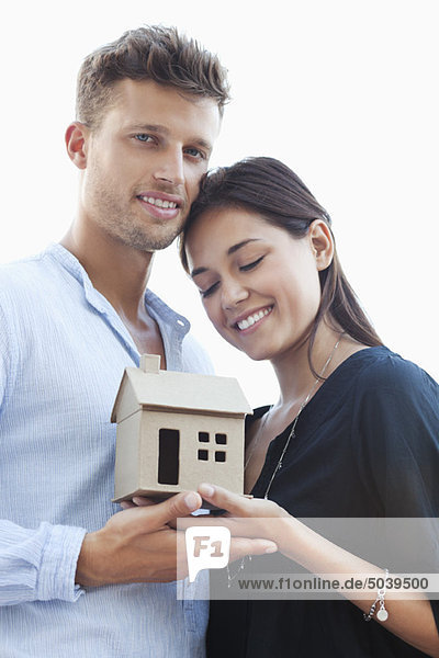 Süßes junges Paar mit kleinem Musterhaus