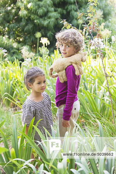 Porträt eines lächelnden Jungen mit kleinem Mädchen im Garten