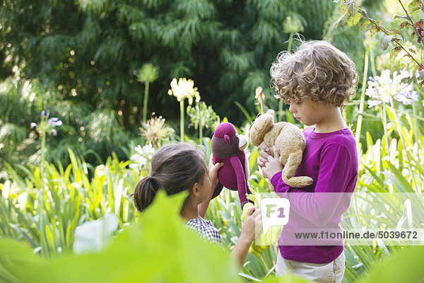 Süßer kleiner Junge steht mit kleinem Mädchen in einem Garten