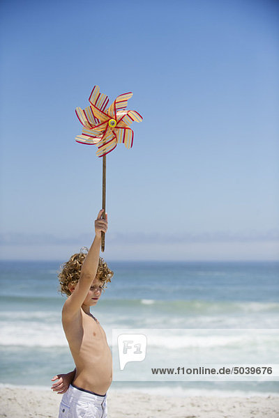Seitenprofil eines Jungen mit einem Windrad am Strand