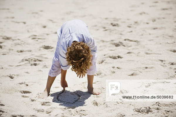 Junge spielt mit Sand am Strand