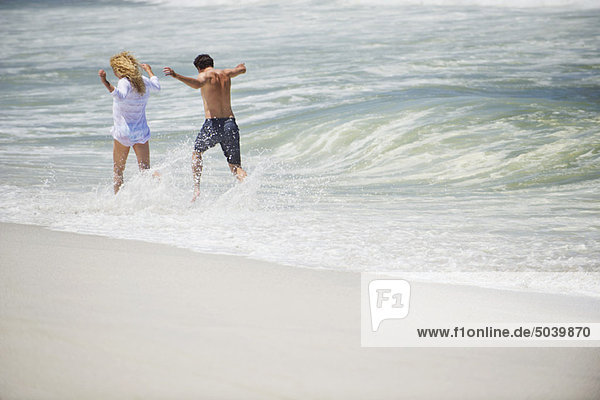 Rückansicht eines am Strand laufenden Paares