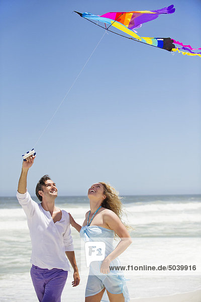 Mittleres erwachsenes Paar beim Drachenfliegen am Strand