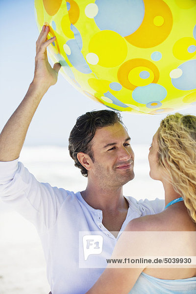 Ein Mann hebt einen Strandball mit einer Frau in seiner Nähe.