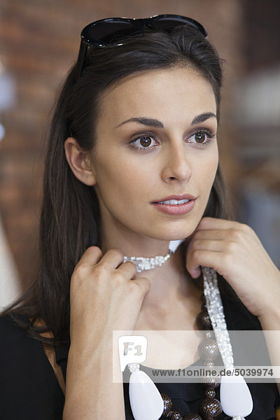 Junge Frau versucht eine Halskette in einem Einkaufszentrum