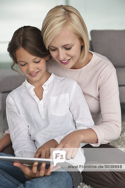 Woman assisting her daughter in using a digital tablet