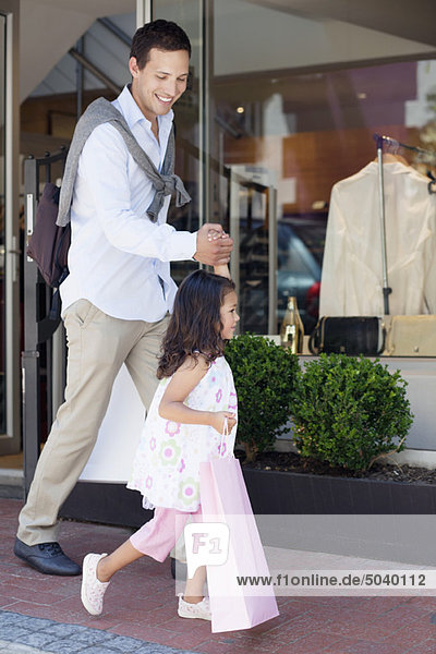 Süßes kleines Mädchen mit ihrem Vater  der aus einem Einkaufszentrum mit Einkaufstaschen kommt.