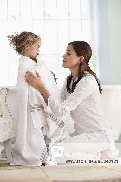 Woman wrapping her daughter in towel after the bath