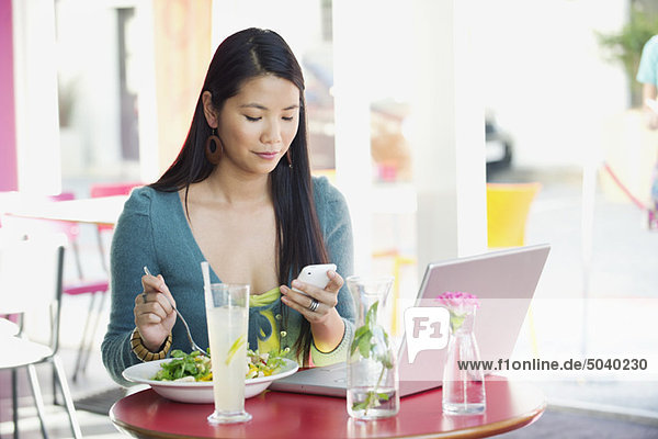 Frau liest Textnachricht beim Essen in einem Restaurant