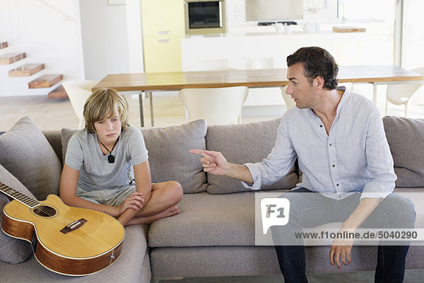 Vater beschwert sich beim Teenager  der zu Hause mit Gitarre sitzt