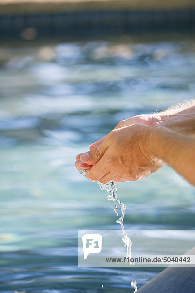 Nahaufnahme der Hand eines Mannes  der das Wasser des Schwimmbeckens berührt