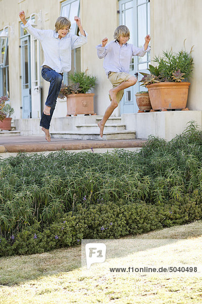Zwei kleine Kinder  die in der Luft gegen das Haus springen.