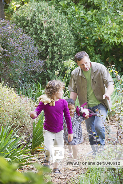 Father with two children walking in a garden