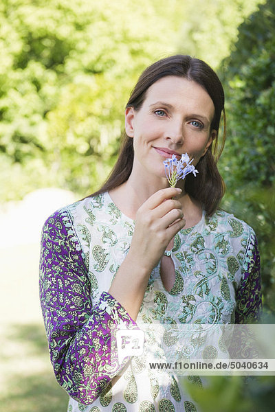 Portrait of a smiling mature woman smelling flowers in garden