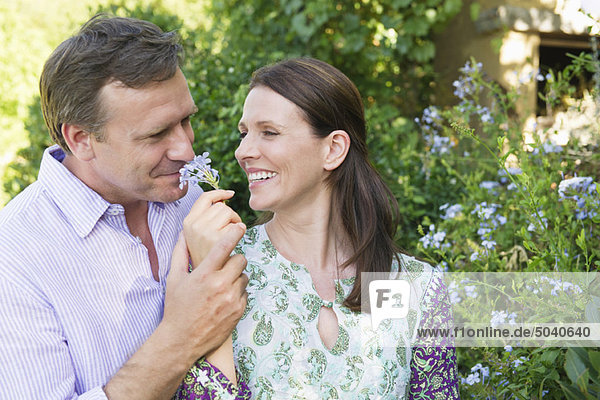 Happy mature couple smelling flowers in the garden