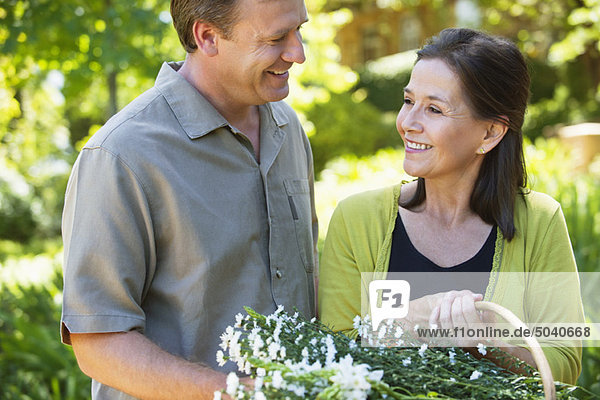 Mann mit seiner Mutter hält einen Blumenkorb im Freien.