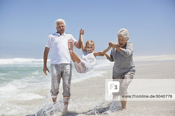 Girl enjoying on the beach with her grandparents