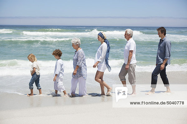 Familienwandern in einer Reihe am schönen Strand mit Kindern