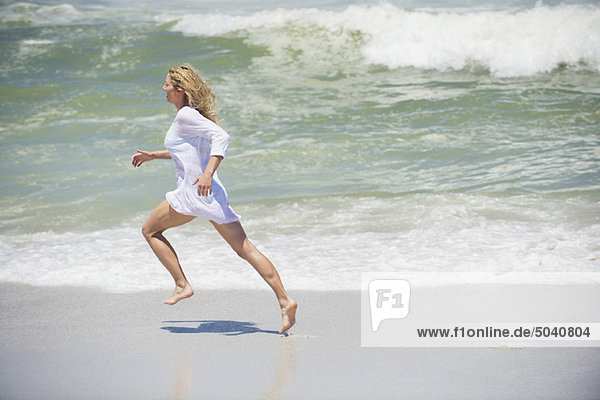 Side profile of a beautiful woman running on the beach