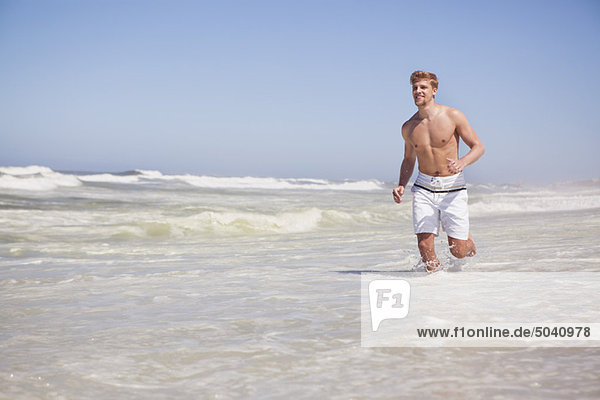 Man running shirtless on the beach