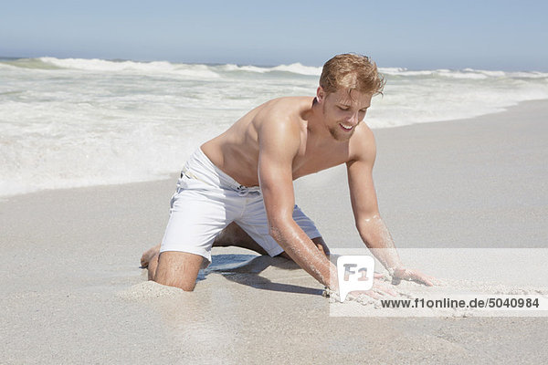 Mann spielt mit Sand am Strand