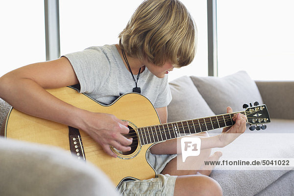 Teenager-Junge spielt zu Hause Gitarre