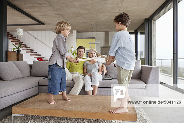 Boys playing with their parents sitting on a couch