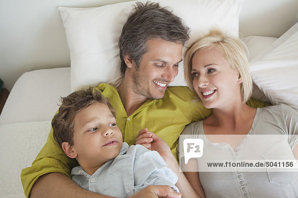 Parents with their son relaxing in bed