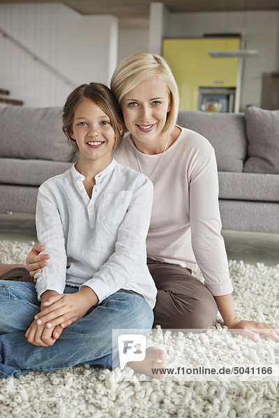 Porträt einer Frau mit ihrer Tochter auf einem Teppich sitzend