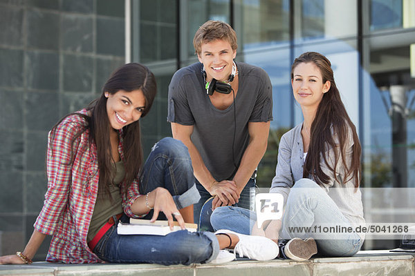 Portrait of smiling young students sitting in campus
