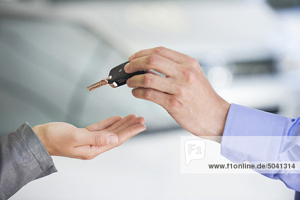 Salesman handing car key to woman